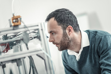 Fototapeta premium Serious skilled technician looking at the 3d printing machine