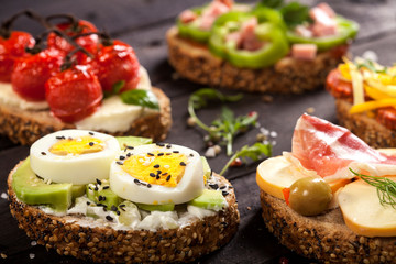 Set of different bruschettas on dark wooden table.