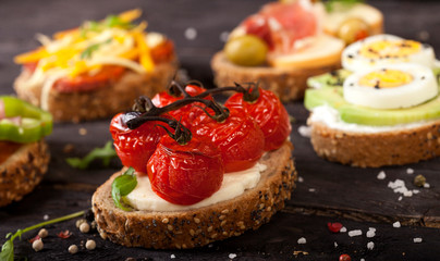 Set of different bruschettas on dark wooden table.