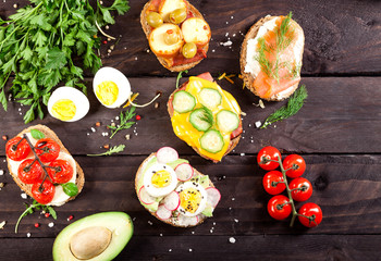 Set of different bruschettas on dark wooden table. Top view and copy space.