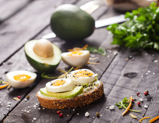 Bruschetta with avocado, cheese, egg, sesame on wooden table