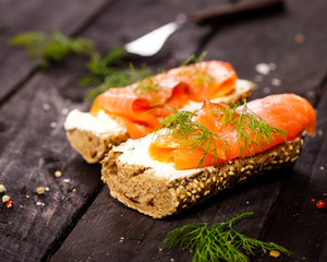 Bruschettas with cream cheese, salmon and dill on wooden table