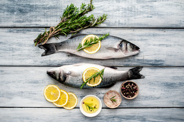 Fresh fish sea bass. Sea bass raw fish with ingredients spices and herbs on wooden background