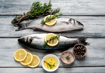 Fresh fish sea bass. Sea bass raw fish with ingredients spices and herbs on wooden background