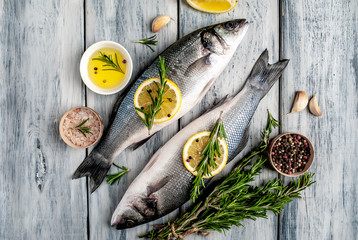 Fresh fish sea bass. Sea bass raw fish with ingredients spices and herbs on wooden background