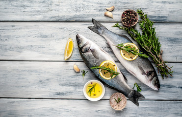 Fresh fish sea bass. Sea bass raw fish with ingredients spices and herbs on wooden background . Top...