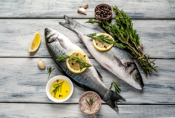 Fresh fish sea bass. Sea bass raw fish with ingredients spices and herbs on wooden background