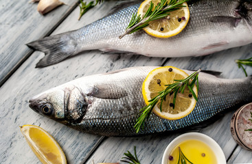 Fresh fish sea bass. Sea bass raw fish with ingredients spices and herbs on wooden background