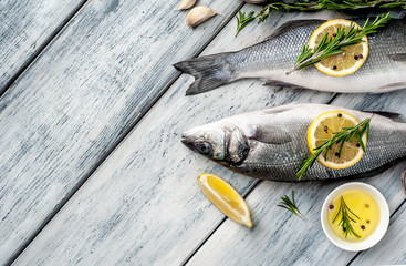 Fresh fish sea bass. Sea bass raw fish with ingredients spices and herbs on wooden background . Top view with copy space. 