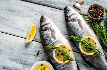 Fresh fish sea bass. Sea bass raw fish with ingredients spices and herbs on wooden background