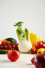 Composition still life of a bunch fresh different seasonal green vegetables avocado, fennel, garlic, onion, tomato, red yellow peper. Concept of healthy food and nutrition.