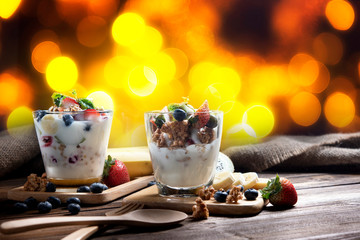 Healthy fitness breakfast, yogurt  Healthy blueberry and raspberry parfaits in glass, scene on dark wooden board with texture