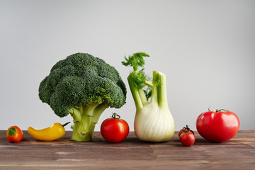 Fresh peper, broccoli, tomato on wooden background. Still life with raw vegetable. Concept of healthy food and nutrition.