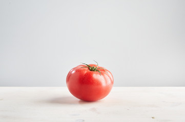 Perfect fresh tomato on light wooden background. Concept of healthy food and nutrition.