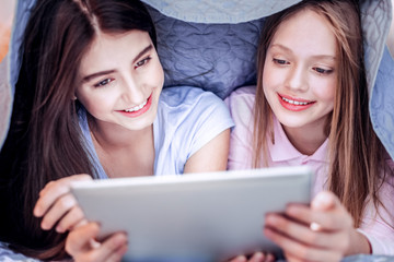 Pretty two girls seeing film under blanket