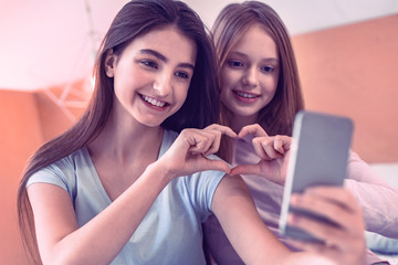 Cheerful teenagers showing heart by their hands