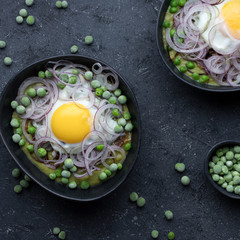 Green pea soup, fried egg and red onion on dark background, top view.