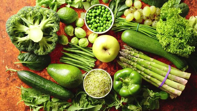 Fresh, natural, green vegetables, fruits and herbs assortment placed on a rusty metal background. Top view.