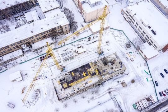 yellow tower cranes at construction site covered with snow. aerial top view image