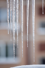 Icicles hang down from the roof edge and thaw from spring heat.