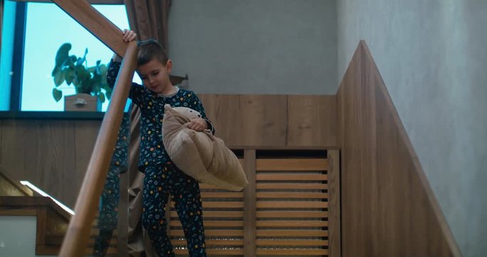 Cute little sleepy kid boy walking down stairs in the morning, with pillow in hands, rubbing his eyes. 4K UHD Blackmagic RAW