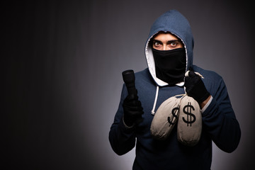 Young gangster in hood on grey background 
