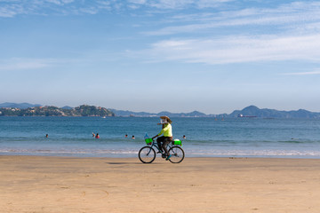El vendedor en bicicleta lleva la bandeja en la playa.