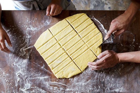 Hand cutting pastry dough on wooden counter