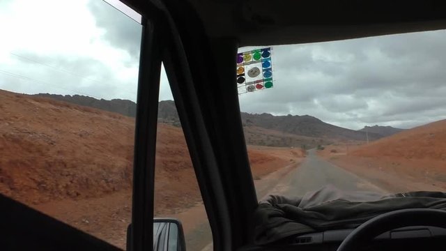 Driving through arid land of red sand by Azrou Rezmouka village in Souss-Massa region of Morocco
