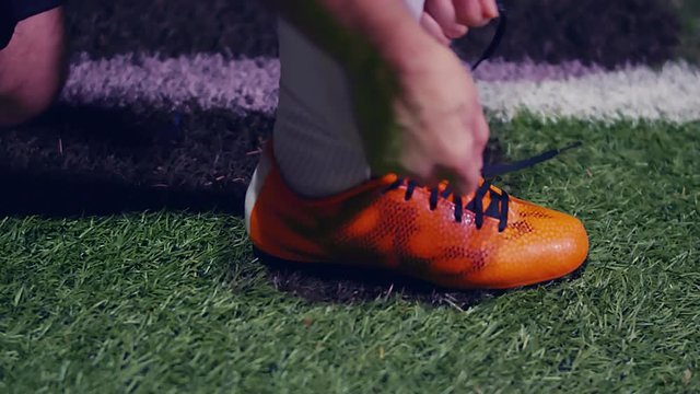 Professional soccer player buckles his boots and enters the field, 4k slow motion