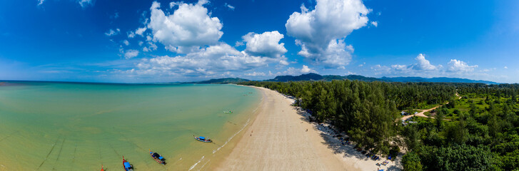 Fototapeta na wymiar Aerial panoramic view of a beautiful tropical beach with traditional boats surrounded by lush greenery (Khao Lak, Thailand)