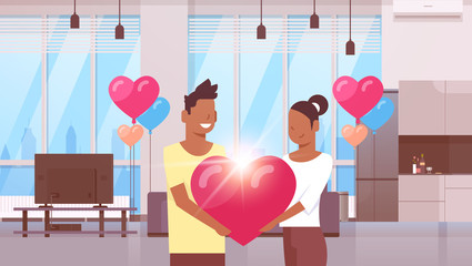 couple holding pink heart shape happy valentines day concept african american man woman lovers standing together modern apartment interior colorful air balloons flat horizontal