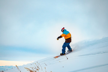 The guy is riding a snowboard. In the mountains in pristine snow.