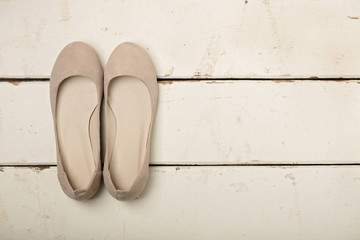 Buttercream women's shoes (ballerinas) on wooden background.