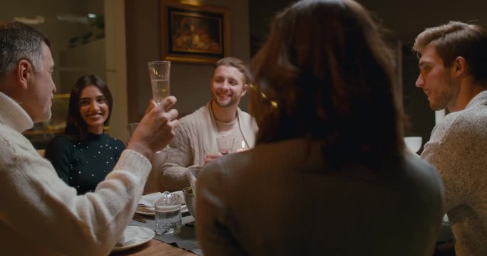 CU Large multi-generation beautiful family clinking glasses while having Christmas or Thanksgiving dinner. 4K UHD Blackmagic RAW