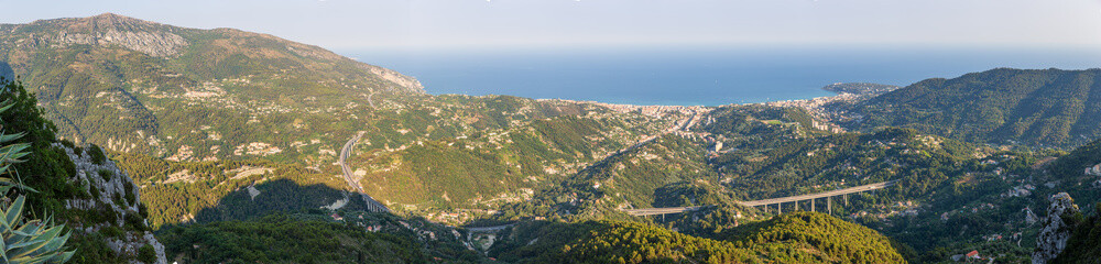 Obraz premium Panoramic view of Menton and the surrounding hillside buildings in front of the A8 bridge road, as captured from Sainte Agnes