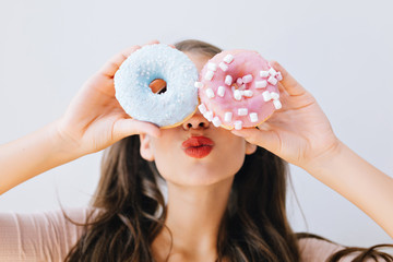 Closeup portrait joyful girl with red lips having fun with colorful donuts against her eyes....