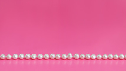 white pearls on pink background with copy space