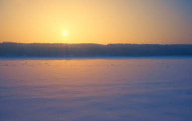 Sun over siberian forest and river Tom under the snow and ice at evening sunset time in winter