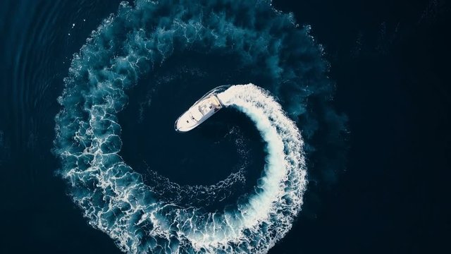 Aerial view of Circle of waves Motor boat on the azure sea of Montenegro against the backdrop of the mountains in summer