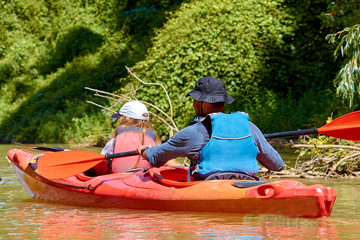 Little girl and her father on a kayak. Father and child paddling in kayak in a Danube river on a sunny summer day. Active water fun during school vacation. Family on kayaks tour.