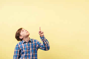 shocked astonished amazed boy points with index finger at empty space, advertisement or product placement, banner or poster template, surprise and amazement, emotion facial expression