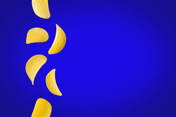 Falling potato chips isolated on blue background. Flying crispy snacks