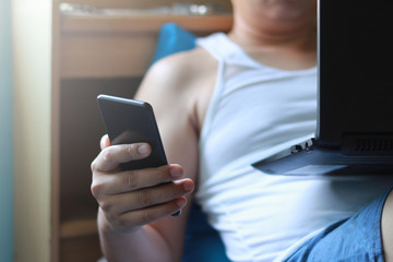 Men use mobile phone and labtop on bed in morning with selective focus