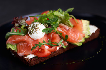 healthy snack, salmon toast for breakfast or lunch with rye bread, sliced avocado and mozzarella. traditional danish open sandwich smorrebrod. whole food and diet, clean eating concept.
