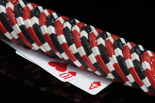 poker chips lie in a row on two playing cards, black background