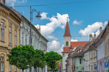 Fototapeta na wymiar Sibiu, Romania - Beautiful street with Reformed Church on a sunny summer day in Sibiu, Romania