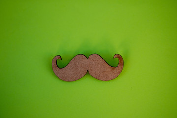 Wooden moustache isolated against green background
