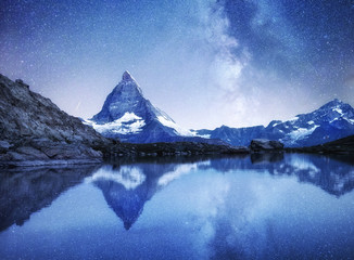 Fototapeta na wymiar Matterhorn and reflection on the water surface at the night time. Milky way above Matterhorn, Switzerland. Beautiful natural landscape in the Switzerland