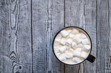 Cup of cocoa with marshmallows on wooden gray background
